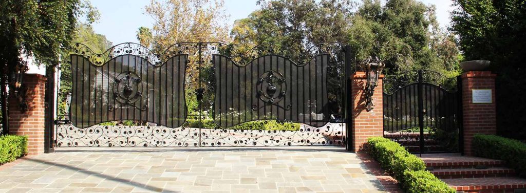 Bifold wrought iron gate with steel mesh and decorated with handmade flower and leaf appliques