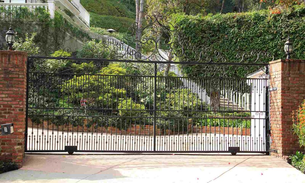 Wrought iron sliding gate with vertical spindles and scrolled top