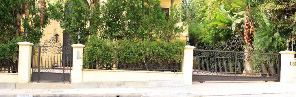Custom hillside wrought iron sliding gate and hinged pedestrian gate