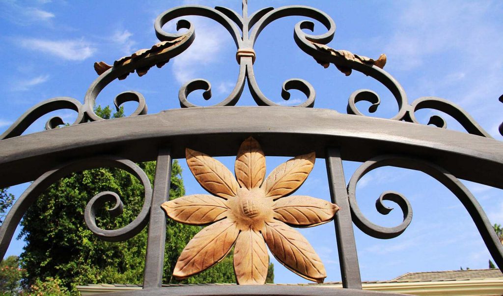 Close up of wrought iron gate accented with tropical gold flowers and leaves